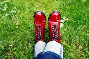 female legs in red boots on green grass