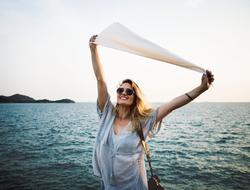 Smiling woman, with sunglasses, posing near the beautiful, turquoise water