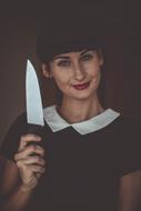 Portrait of a smiling woman in black and white clothing, with the kitchen knife