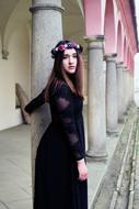 Girl in black dress and colorful flower wreath near the columns