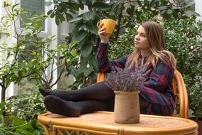 young Girl with mug in hand sits with legs on table outdoor