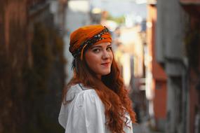 woman with red hair in a turban on a city street