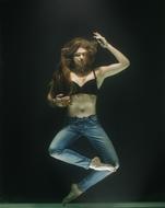 Girl in black bra and jeans, posing underwater, at black background