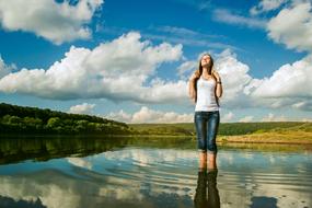 Woman, in the river, with ripple, among the colorful plants, under the blue sky with clouds