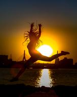 Silhouette of a dancing girl, at beautiful and colorful sunset on the sea