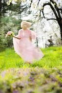 girl in a pink dress runs in the meadow