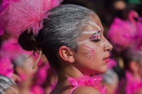 girl with pink feathers at the carnival in profile