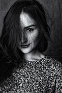 Black and white portrait of the beautiful, smiling woman with half of the face covered with hair