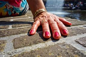 Close-up of the hand, with the shiny, red nails, beautiful ring and bracelet, in light