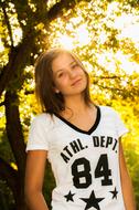 Portrait of a posing girl, in white and black t-shirt, among the colorful plants in sunlight