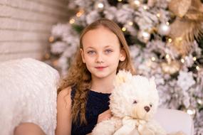 little girl with a teddy bear at a christmas photo shoot