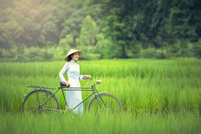 Woman with Bicycle on Green field