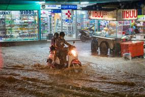 couple riding a moped during a flood at night