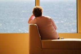 pensive woman looks out of the window at the sea