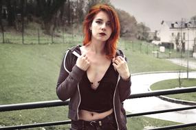 Portrait of the red haired woman, posing near the beautiful city