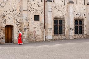 Walking girl in a red dress and white head cover on a city street