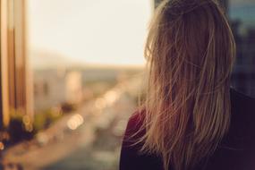 blonde looks out the open window