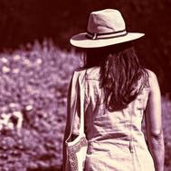 woman with long hair and a bag over her shoulder in a blooming garden