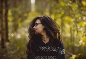 Smiling woman, with the glasses, posing among the green plants, in light