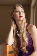 beautiful blonde woman with red lips posing on a chair