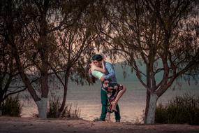 a couple in love stands near a tree near the sea