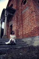 woman in white on the stairs near the ruins of the church