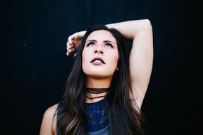 photo of brunette with dark makeup with raised hand