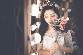 young asian girl wearing white dress holds artificial flowers