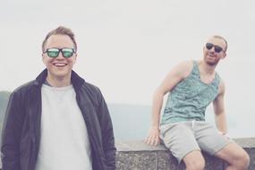 Portrait of the smiling men with sunglasses, on the shore