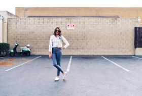 photo of a girl in a white sweater and jeans in the parking lot