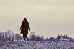 Back vire of the person, walking on the beautiful landscape with the field, trees and house, in black and white colors