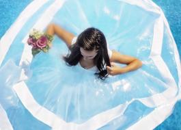 bride with a bouquet in a floating dress on the water