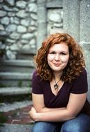 Portrait of a smiling girl with ginger, curly hair, sitting on the stairs