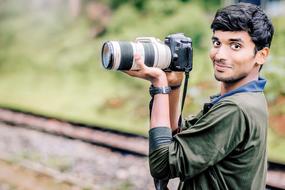 young asian Man with Canon Camera in hands outdoor