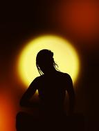 Silhouette of a woman in meditation at background with colorful and beautiful bokeh lights