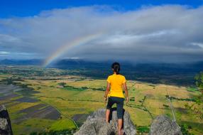 Woman, standing on the beautiful and colorful cliff, on the shore with rainbow