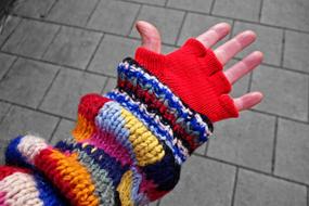outstretched hand and multicolored knit sweater