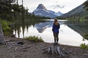 woman looking at scenic mountain lake, usa, montana, glacier national park