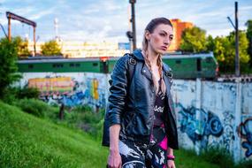 Girl, on the green hill, near the colorful graffiti, near the green and white train