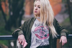 Portrait of the blonde woman, posing on the fence