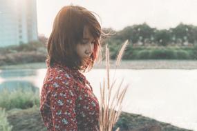 sad young asian girl with grass in hands outdoor