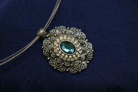 Close-up of the beautiful necklace with turquoise gem, at blue background