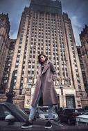 photo of a girl in a coat against a skyscraper