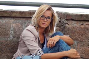 Portrait of a sitting, blonde woman with glasses