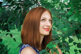smiling young Girl posing at green tree