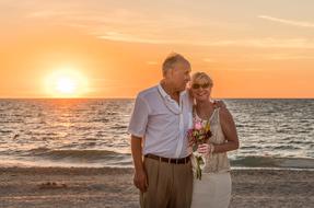 elderly bride and groom on the evening beach