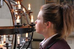 Profile portrait of a young woman near the burning candles in the church