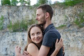 Hugging couple in love, near the beautiful rocks with green plants