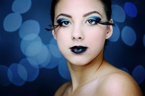 Portrait of the woman, with the blue makeup, at background with the blue bokeh lights