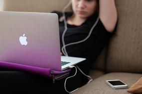 Girl with headphones at Apple laptop Computer